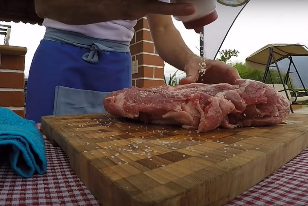 На деревянной доске повар солит мясо