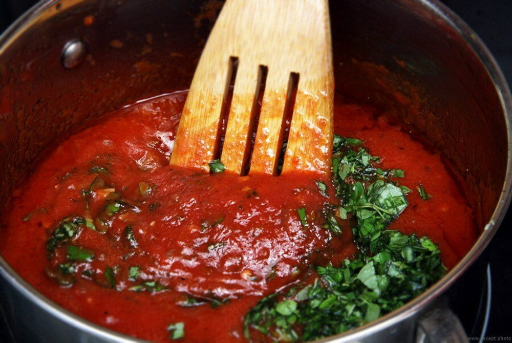 В кастрюле деревянной лопаткой перемешивают томатный соус