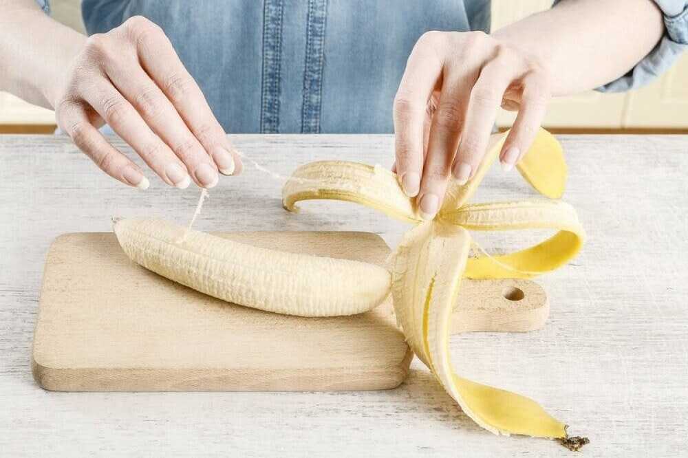 Девушка очищает банан от кожуры