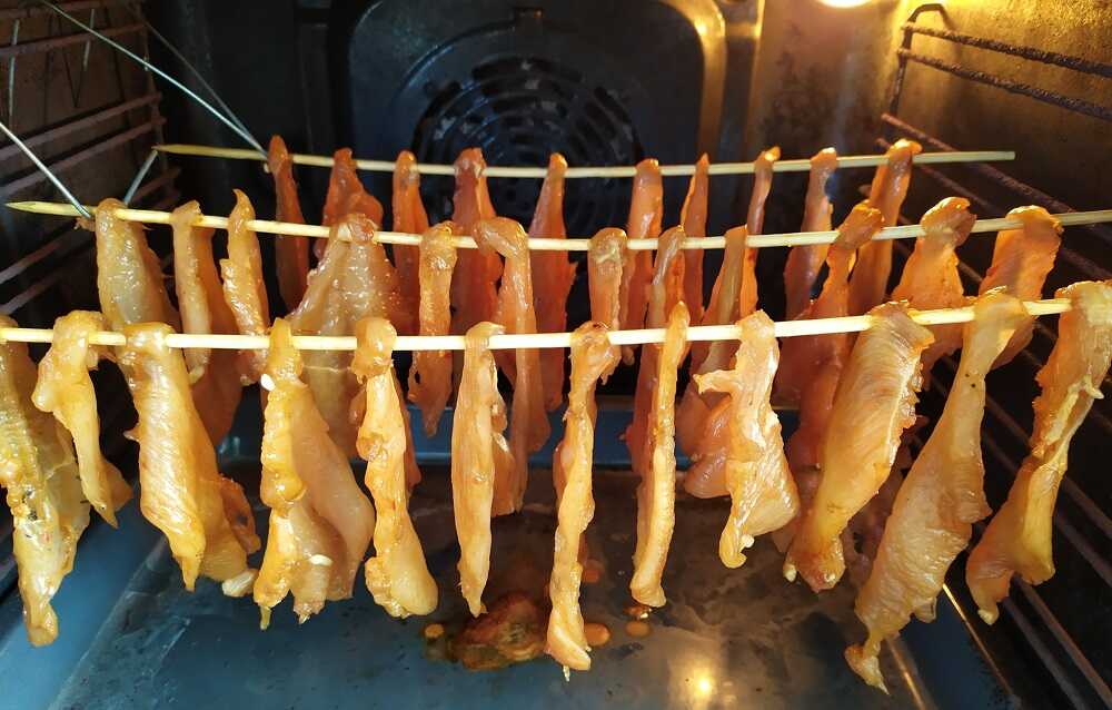 Куриные кусочки висят на решетке в духовке