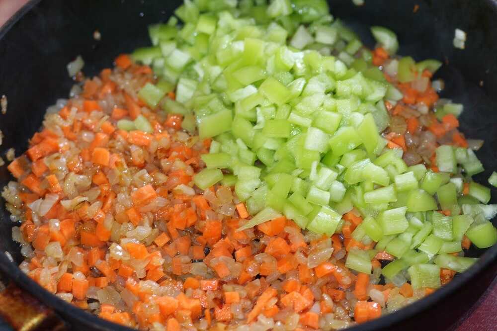 Лук, морковь и сельдерей жарятся на сковороде