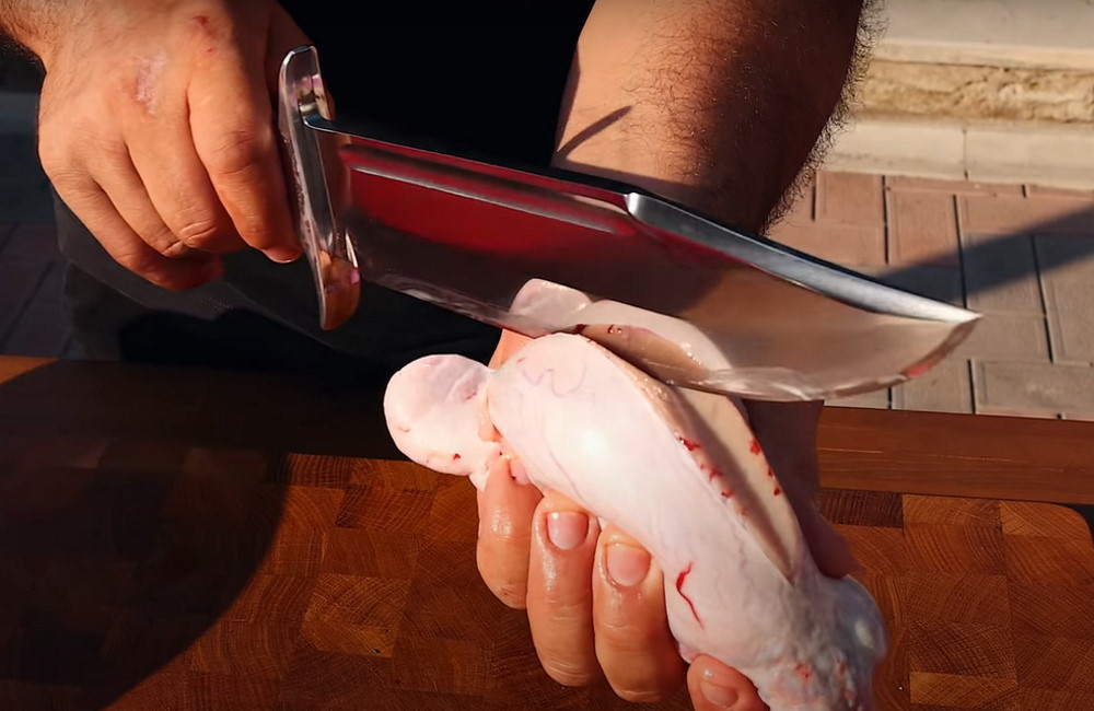 Повар разрезает ножом бычьи яйца
