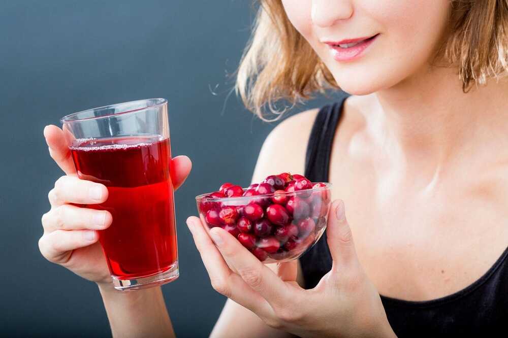 У девушки в руках стакан с напитком из боярышника и ягоды