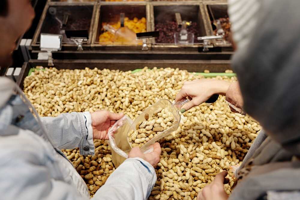 Женщина покупает арахис на рынке