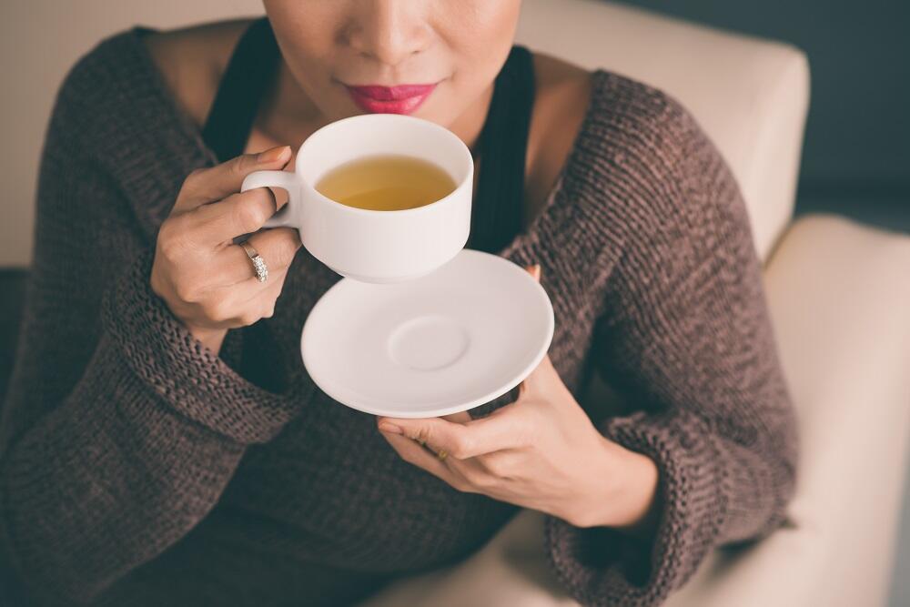 Женщина пьет чай из белой кружки