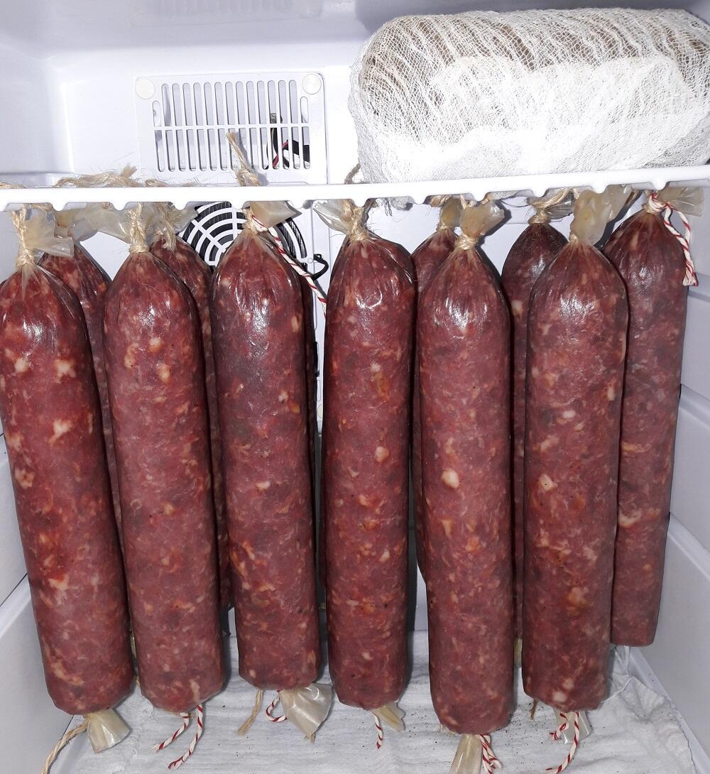 Батоны колбасы висят в холодильнике