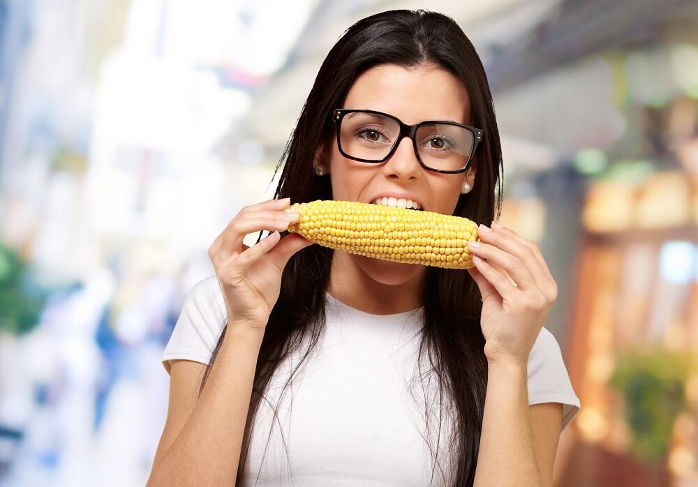 Девушка ест кукурузный початок
