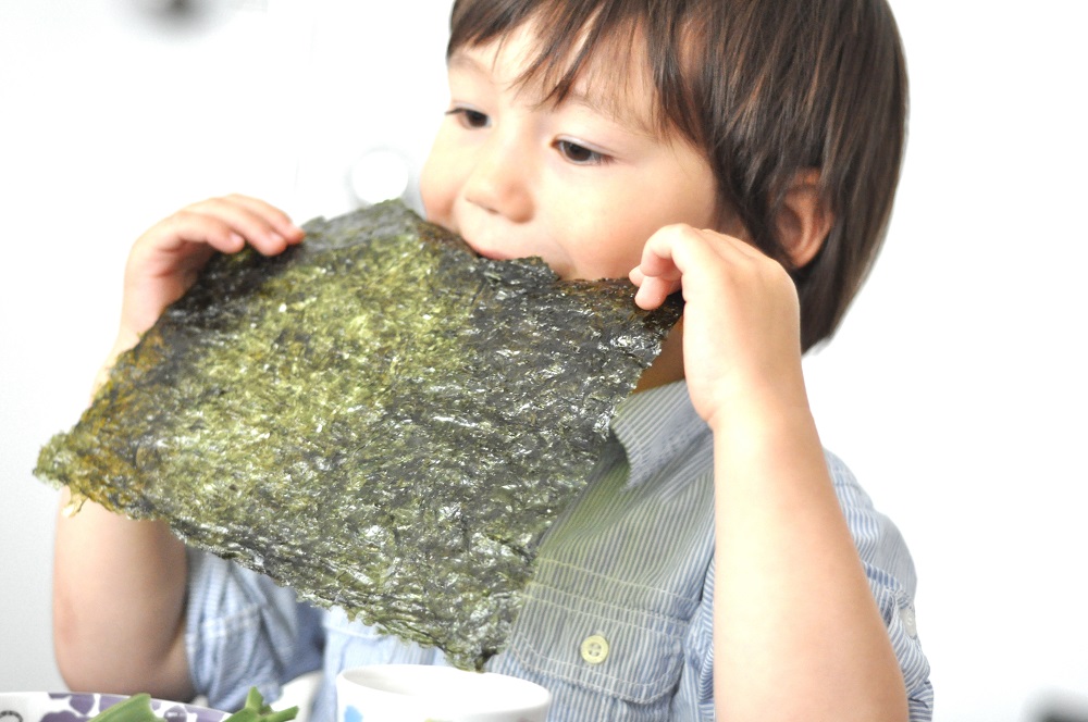 Ребенок ест сушеную морскую капусту