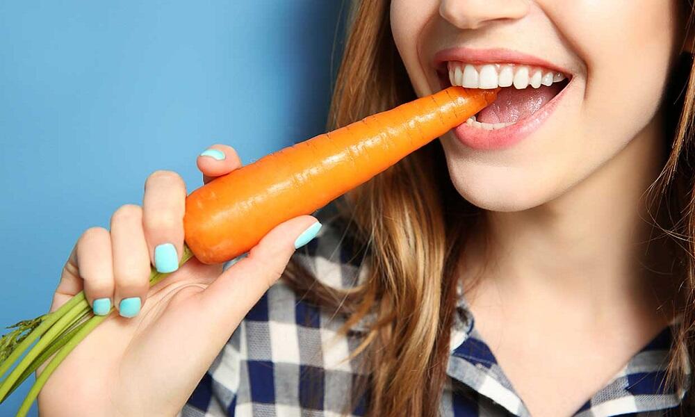 Девушка ест морковку