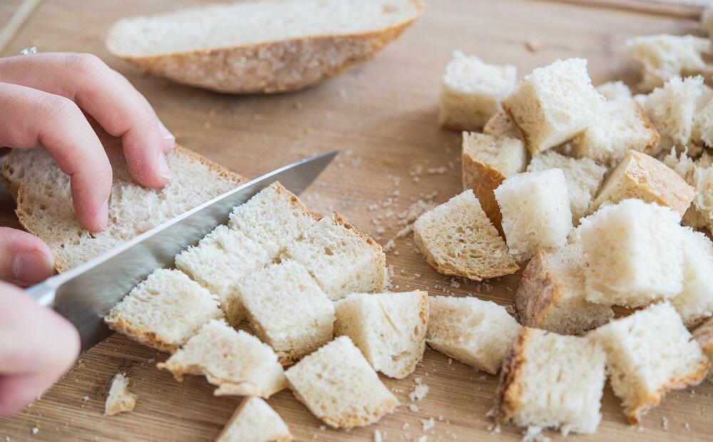 Девушка режет хлеб ножом