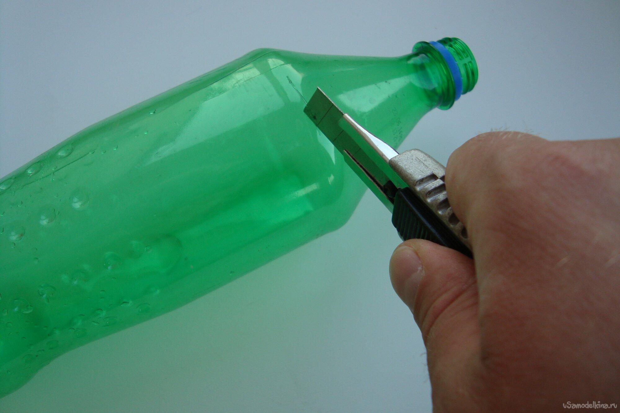 Человек срезает горлышко на пластиковой бутылке